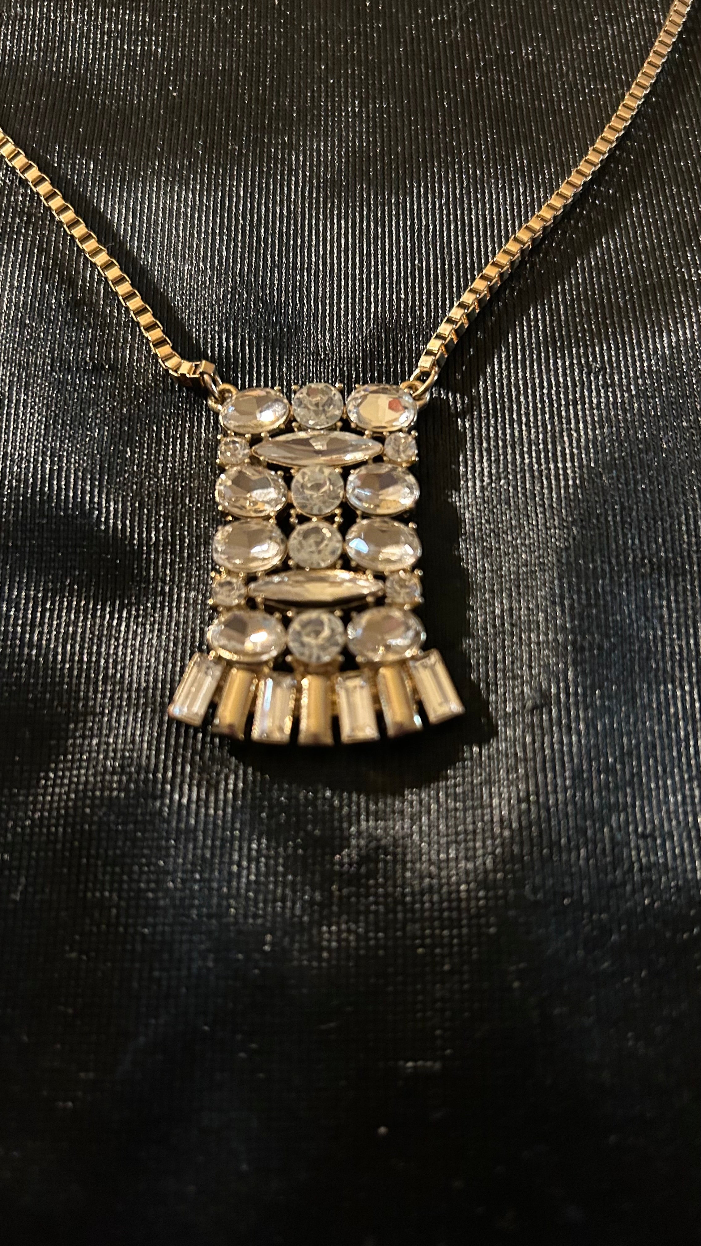 vintage-style gold-tone piece featuring a rectangular, crystal-encrusted pendant