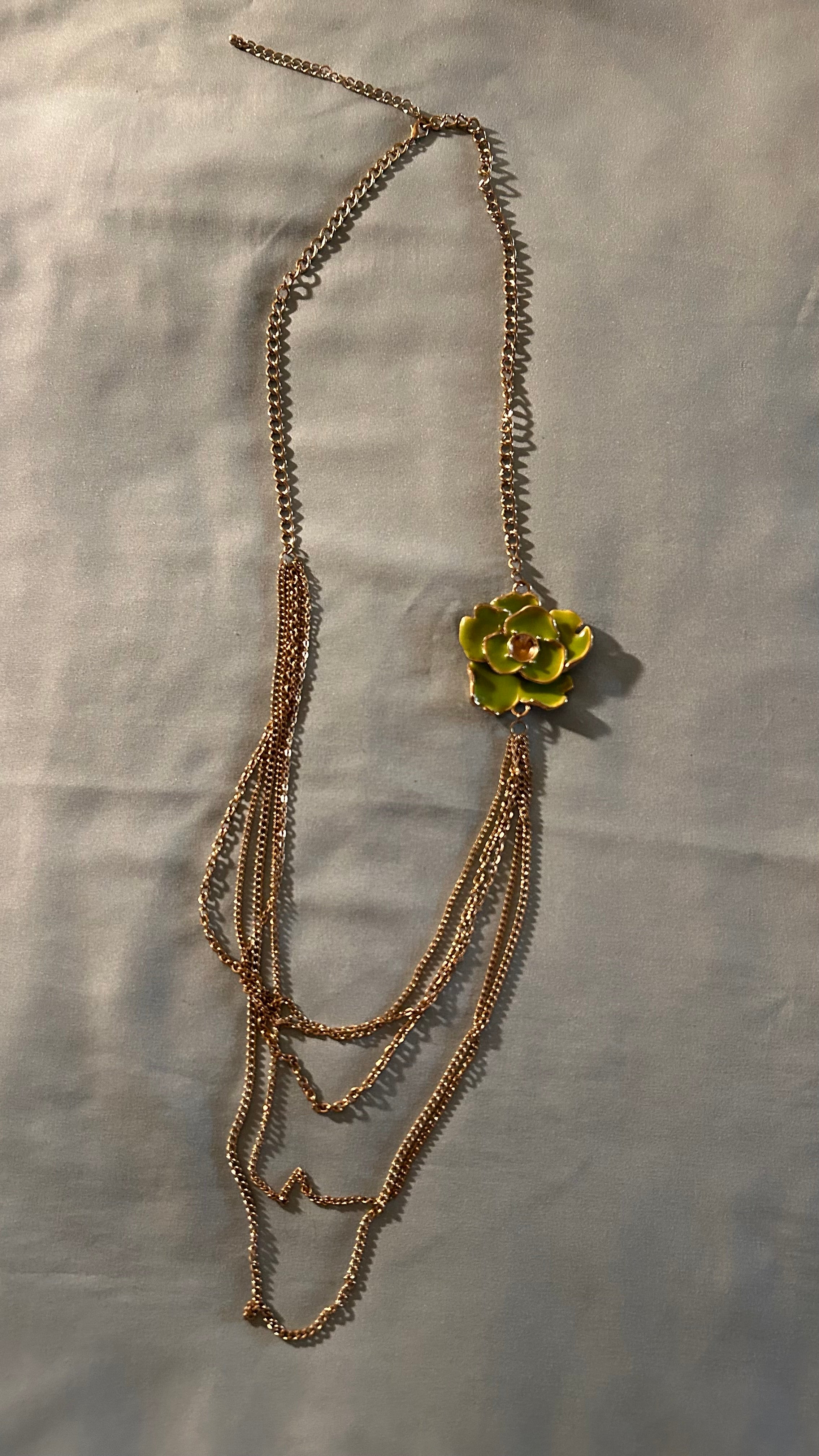 Gold-tone multi-chain accessory featuring a light green floral charm