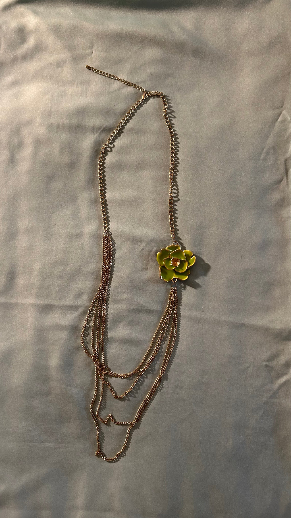 Gold-tone multi-chain accessory featuring a light green floral charm