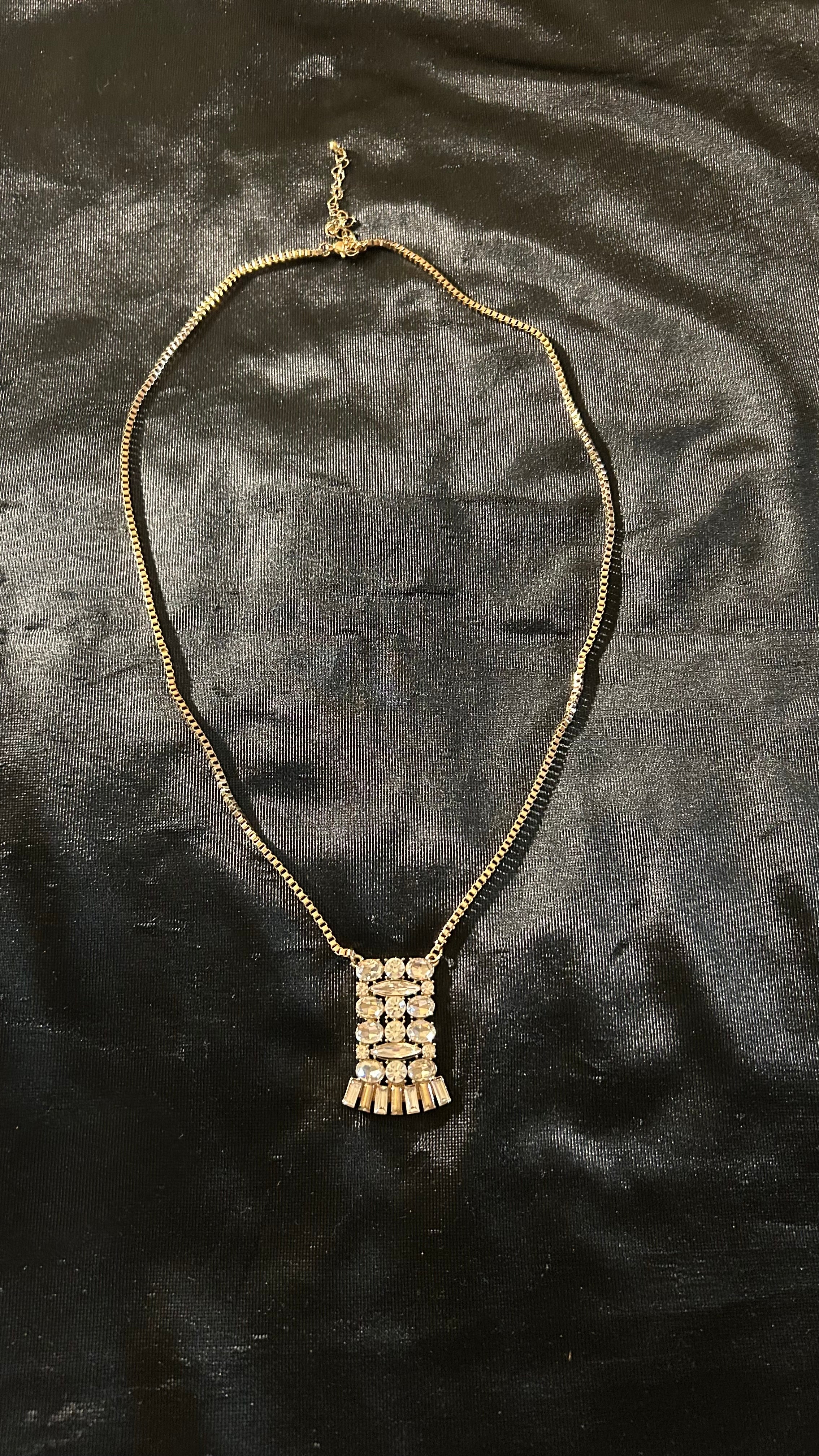 vintage-style gold-tone piece featuring a rectangular, crystal-encrusted pendant